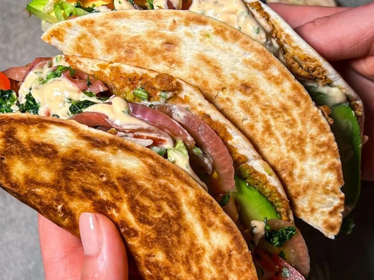 Two veggie Smashburger tacos held in someone’s hand with the filling visible. 