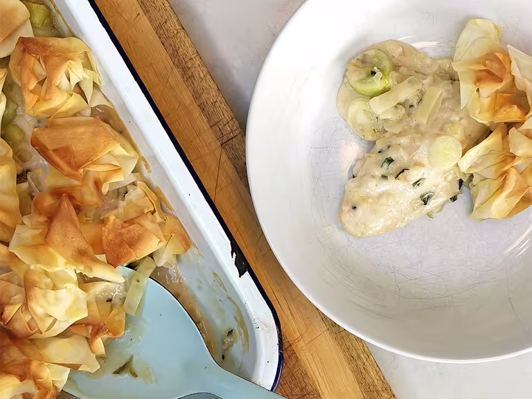 A baking tray containing filo pastry pie with a bowl filled with a serving of crispy filo pie made with Quorn Fillets.