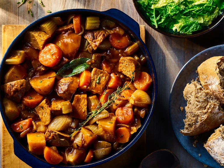 Vegetarian Irish Stew made using Quorn Beef Roast served in a dark dish with a side of bread.