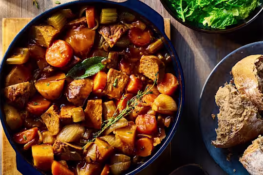Vegetarian Irish Stew made using Quorn Beef Roast served in a dark dish with a side of bread.