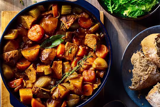 Vegetarian Irish Stew made using Quorn Beef Roast served in a dark dish with a side of bread.