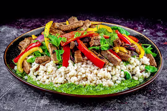Pearl bailey, pepper and Quorn steak strip salad with salsa served on a rounded dish.