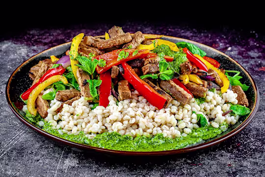 Pearl bailey, pepper and Quorn steak strip salad with salsa served on a rounded dish.