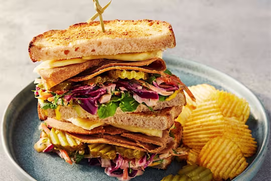 Quorn Roast Beef Vegetarian Reuben sandwich displaying the fillings with crisps on the side.
