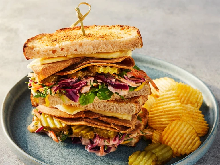 Quorn Roast Beef Vegetarian Reuben sandwich displaying the fillings with crisps on the side.
