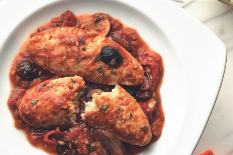 Meatless Quorn Fillets chicken cacciatore served in a dish, with one fillet half cut, garnished with olives