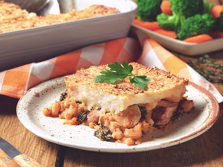 Veggie Sausage and Bean Pie, made with Quorn sausages, tomato, beans, carrot and onion, served on a plate with mixed veg.