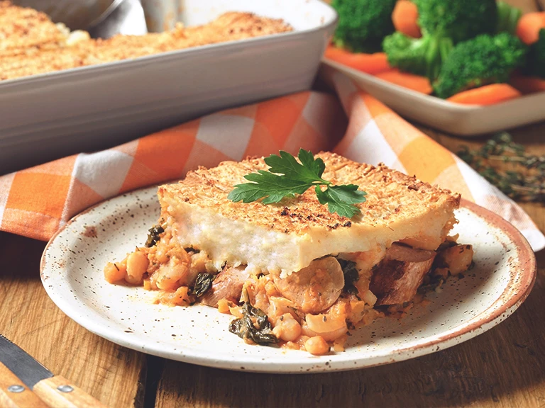 Veggie Sausage and Bean Pie, made with Quorn sausages, tomato, beans, carrot and onion, served on a plate with mixed veg.