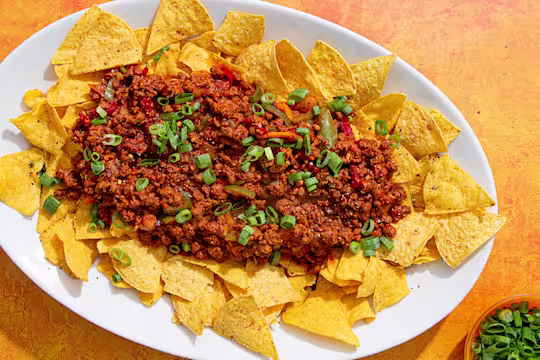 Tray with tortilla chips topped with Quorn Mince chilli con carne and spring onions