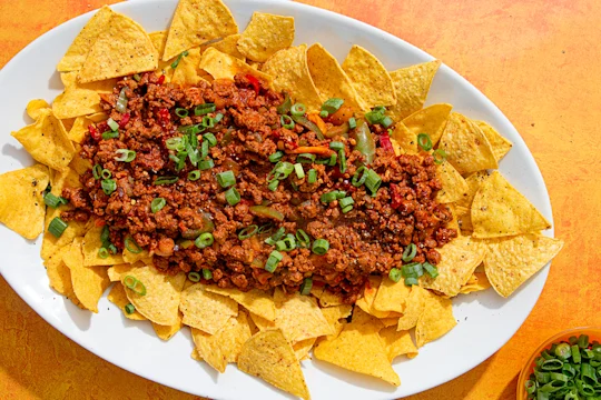 Tray with tortilla chips topped with Quorn Mince chilli con carne and spring onions
