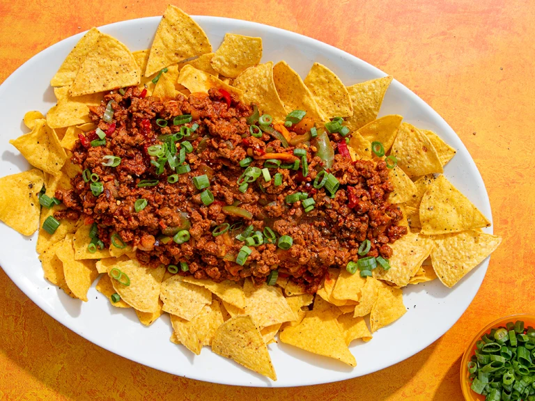 Tray with tortilla chips topped with Quorn Mince chilli con carne and spring onions 