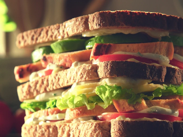 A double-decker sandwich filed with lettuce, tomatoes, avocado, Quorn Fillets, and a yogurt dressing.