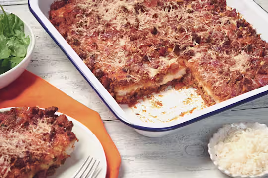 Sardinia veggie bake made with Quorn Mince topped with Parmesan cheese served in a roasting tray with a portion taken out