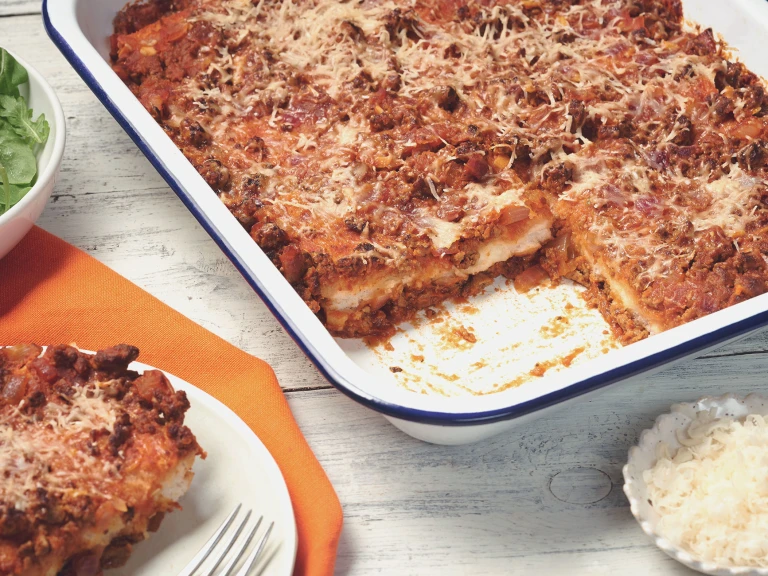 Sardinia veggie bake made with Quorn Mince topped with Parmesan cheese served in a roasting tray with a portion taken out