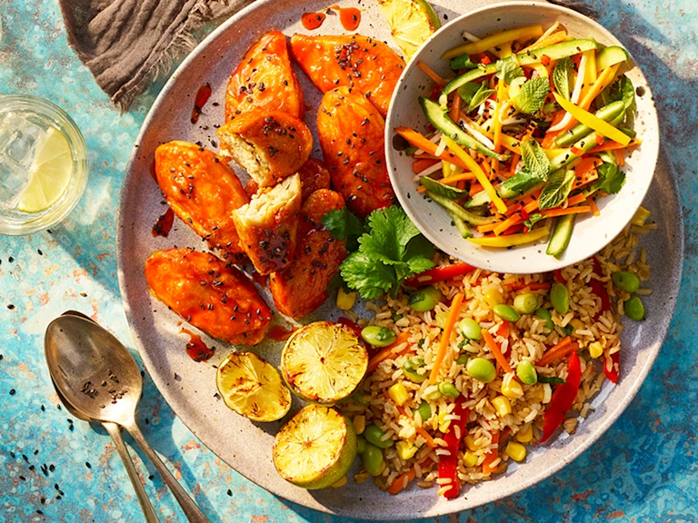 Quorn Vegan Hot and Spicy Burger layered on top of salad and half a bun topped with bbq beans with a pot of beans on the side