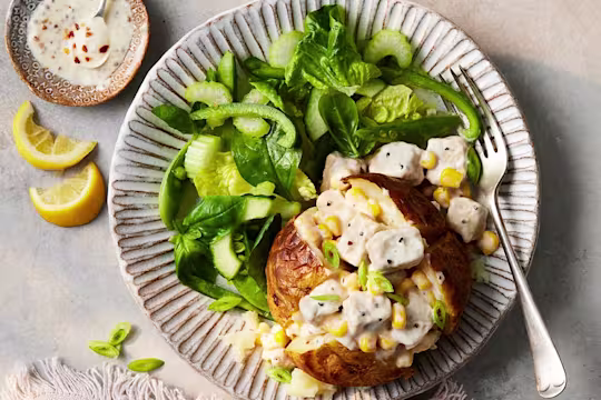 A Vegetarian Chicken and Sweetcorn Loaded Jacket Potato paired alongside a salad of spinach and green peppers.
