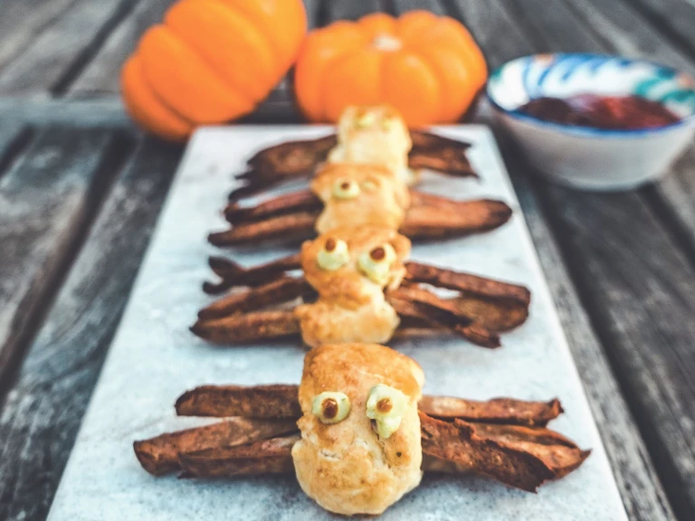 Slices of Quorn Sausage wrapped in puff pastry with guacamole and pumpkin eyes to resemble spiders.