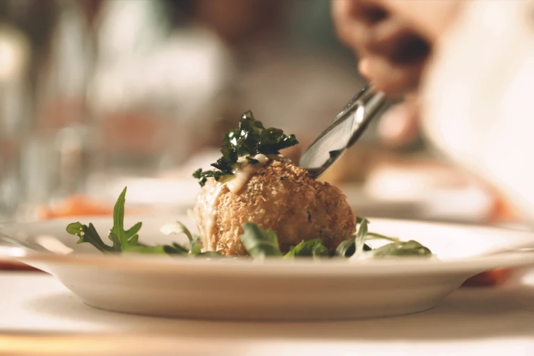 A vegetarian arancini rice ball on a bed of greens.