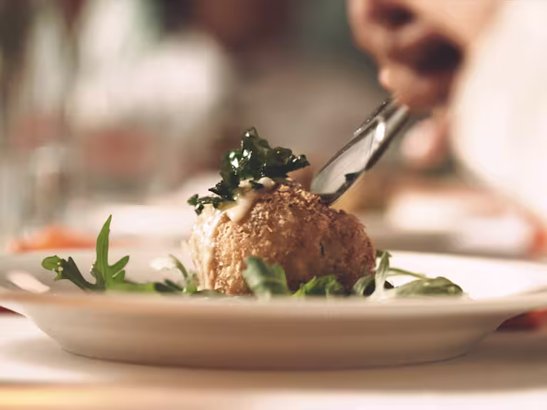 A vegetarian arancini rice ball on a bed of greens.