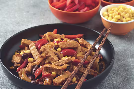 Vegetarian Mexican stir fry made with Quorn Steak strips, peppers, sweetcorn and kidney beans served in a black bowl with chopsticks