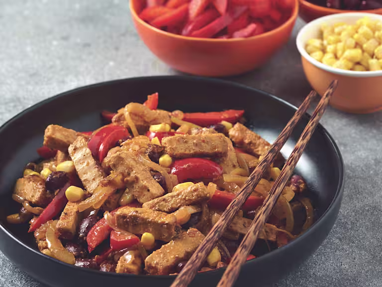 Vegetarian Mexican stir fry made with Quorn Steak strips, peppers, sweetcorn and kidney beans served in a black bowl with chopsticks