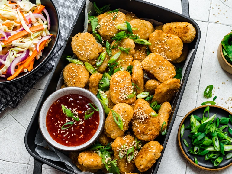 Quorn meatless nuggets served in a baking tray with sweet chili dip and a side of slaw.
