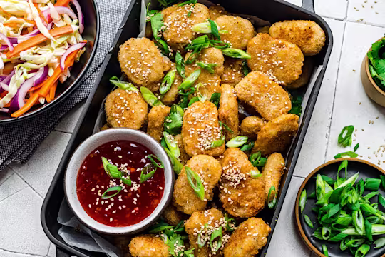 Quorn meatless nuggets served in a baking tray with sweet chili dip and a side of slaw.