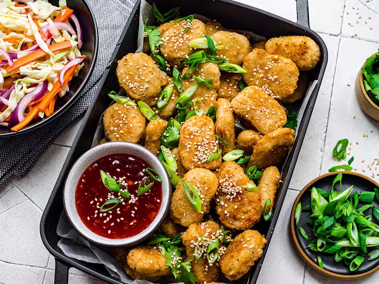 Quorn meatless nuggets served in a baking tray with sweet chili dip and a side of slaw.