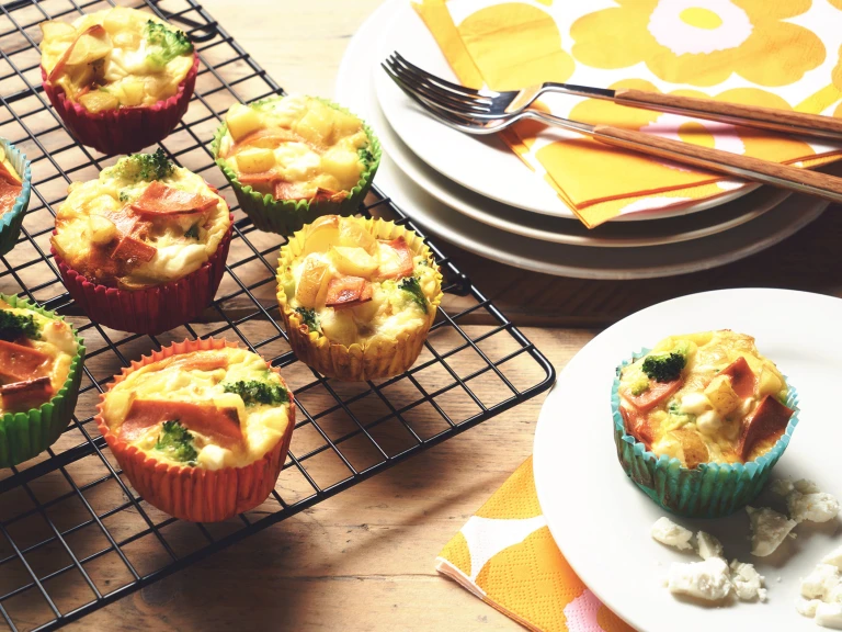 Veggie frittatas made with Quorn Vegetarian Bacon Slices, potato and broccoli in muffin cases on a wire rack with one on a plate