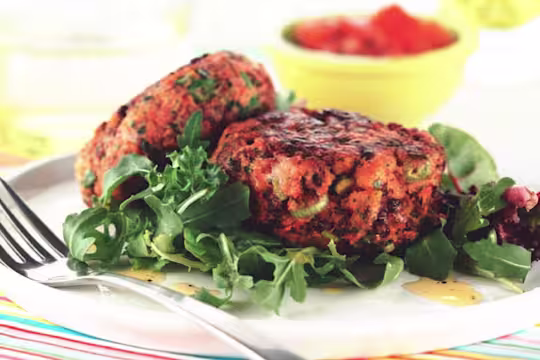 Homemade burger recipe made with vegetarian Quorn Mince and Fruit served on a bed of salad on a white plate with a fork
