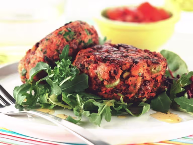 Homemade burger recipe made with vegetarian Quorn Mince and Fruit served on a bed of salad on a white plate with a fork