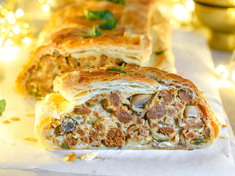 Vegetarian Wellington, made with Quorn Mince, onion, breadcrumbs, chilli, herbs, murshrooms, and served with sprouts, chutney on a plate.