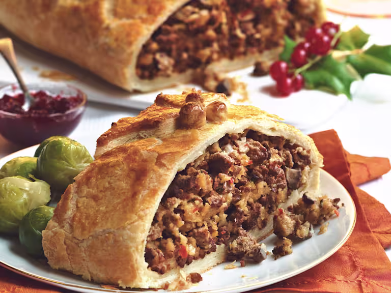 Vegetarian Wellington, made with Quorn Mince, onion, breadcrumbs, chilli, herbs, murshrooms, and served with sprouts, chutney on a plate.