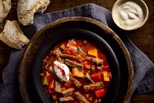 Vegetarian Goulash in pot next to chunks of bread and a creamy dip