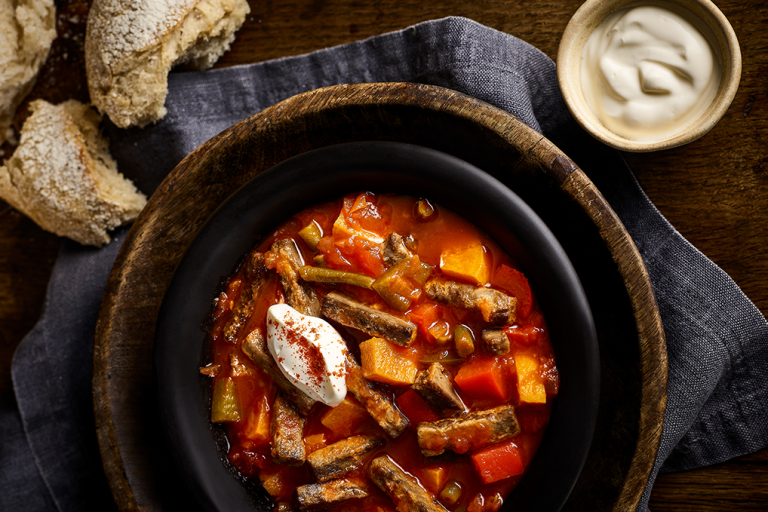Vegetarian Goulash in pot next to chunks of bread and a creamy dip