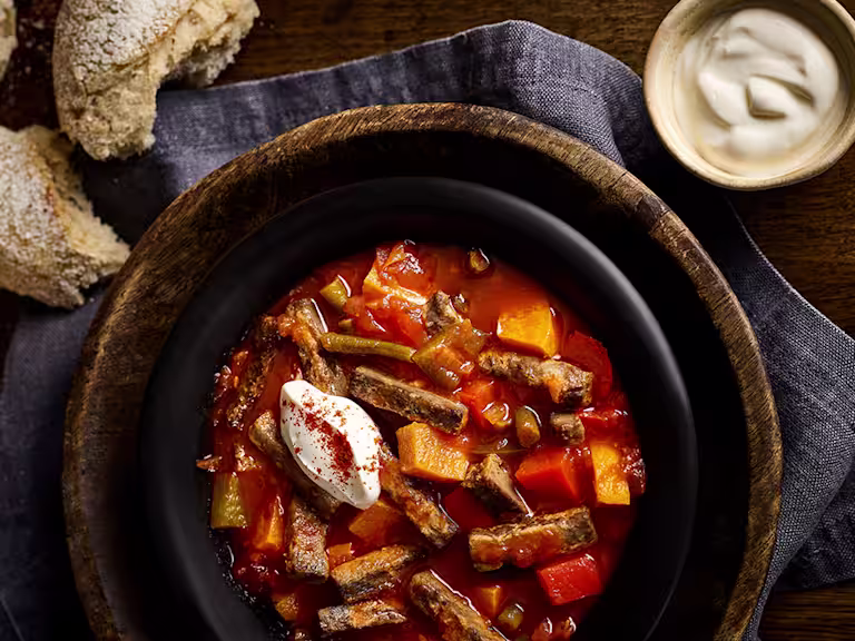 Vegetarian Goulash in pot next to chunks of bread and a creamy dip