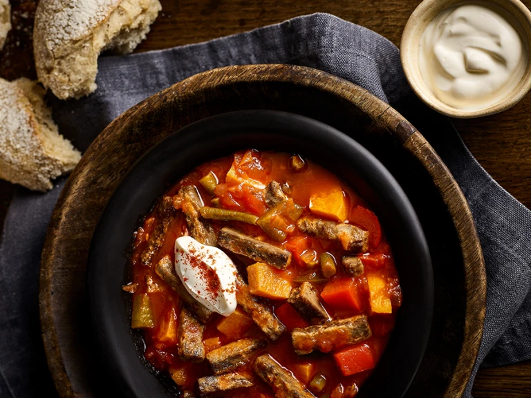 Vegetarian Goulash in pot next to chunks of bread and a creamy dip