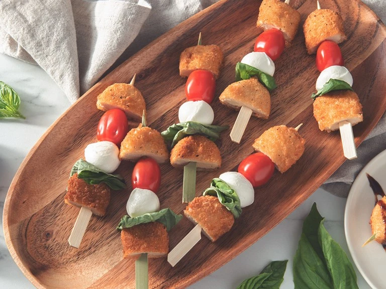Quorn Caprese Skewers served on a wooden dish.
