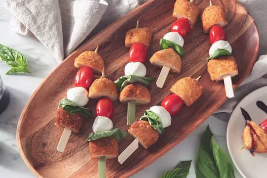 Vegetarian skewers with Quorn crispy nuggets, cherry tomatoes, mozzarella balls, and basil served on a wooden platter