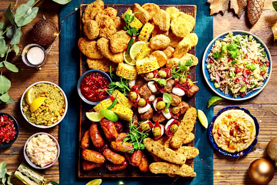 A vibrant Quorn Grazing Board featuring a variety of meat-free options like breaded pieces, grilled corn, olives, hummus, rice salad, and a selection of dips.