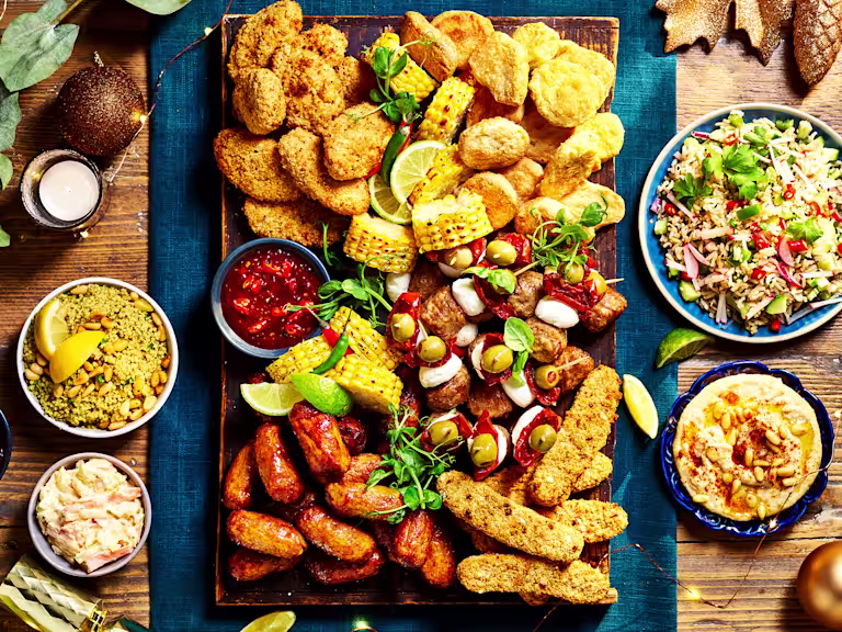 A vibrant Quorn Grazing Board featuring a variety of meat-free options like breaded pieces, grilled corn, olives, hummus, rice salad, and a selection of dips.