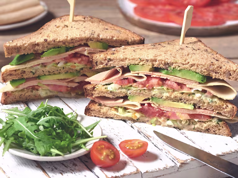 Club sandwich with Quorn Vegan Chicken Free Slices and Vegan Smoky Ham Free Slices layered with tomato and avocado