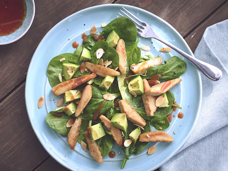 Spenat- och avokadosallad toppad med Quorn minifiléer på blå tallrik.