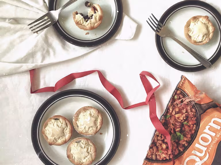Mince pie recipe made with Quorn Mince served on white plates with black rim, dessert forks and a strand of ribbon on the table