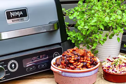 Smoked Vegetarian Sausage and Beans next to a bowl of homemade slaw and a green plant.