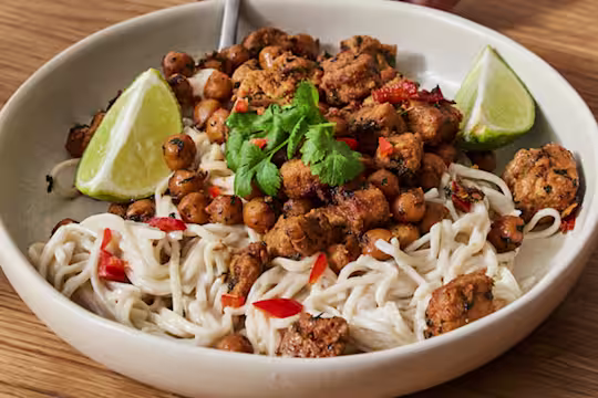 En stor skål med Quorn vegetariska asiatiska gryta med krämiga nudlar serverad i en krämfärgad skål