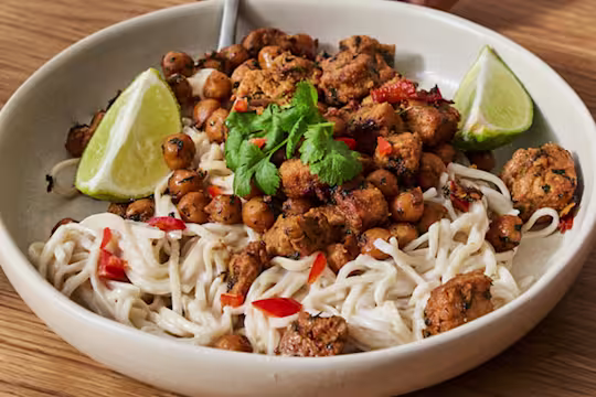 En stor skål med Quorn vegetariska asiatiska gryta med krämiga nudlar serverad i en krämfärgad skål