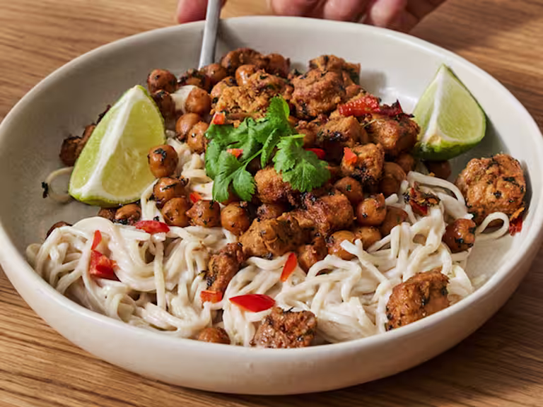 En stor skål med Quorn vegetariska asiatiska gryta med krämiga nudlar serverad i en krämfärgad skål