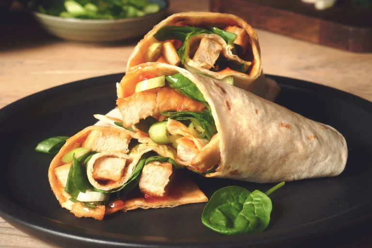Easy lunch idea of sweet chilli wraps made with vegetarian Quorn Roasted Sliced Fillets served on a black plate