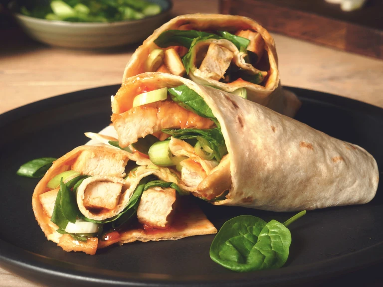 Easy lunch idea of sweet chilli wraps made with vegetarian Quorn Roasted Sliced Fillets served on a black plate